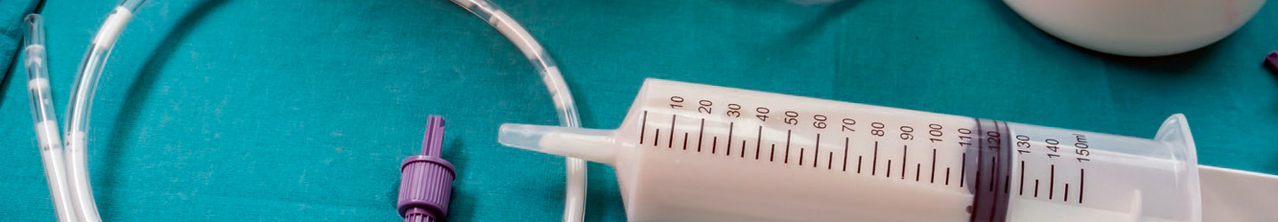 Tube feeding syringes and tubes sit strewn across a surgical table