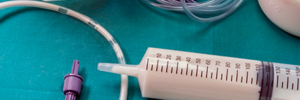 Tube feeding syringes and tubes sit strewn across a surgical table