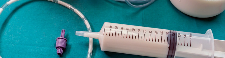 Tube feeding syringes and tubes sit strewn across a surgical table