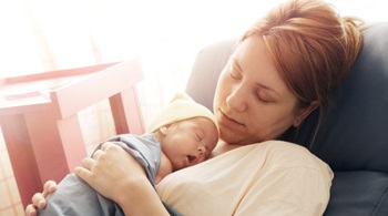 Premature baby born at 25th week of pregnancy sleeping with mother during the kangaroo care session in hospital. Genuine emotions, real scene. Natural light.